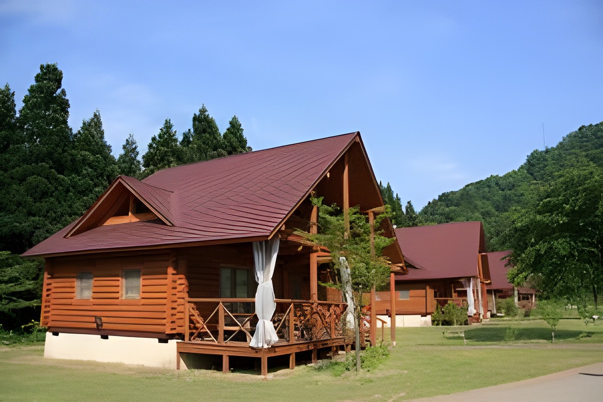 Log-cabin cottages with red roofs among the trees at Ichirino.
